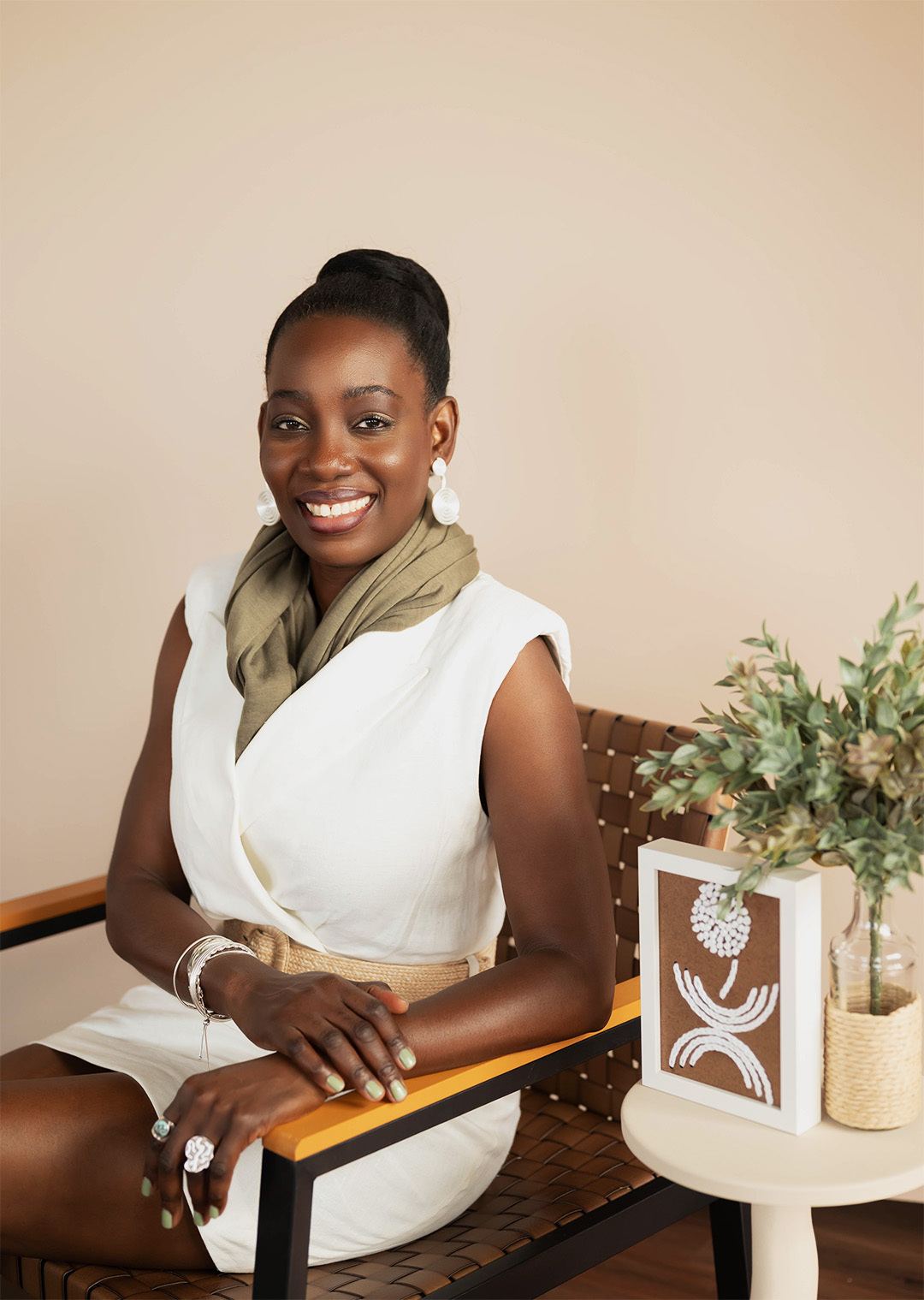 Artist Atinuke Adeleke founder lead designer of dallas based brand Zuri Perle website pic Artist Atinuke Adeleke wearing the igba aye Fumi 3D printed earrings sitting on a chair